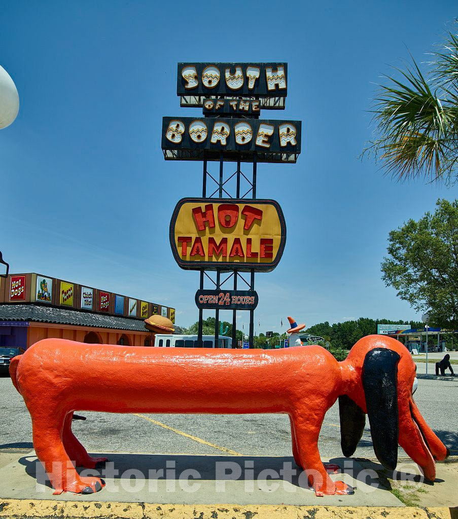 Photograph- A"weiner dog" figure, mounted near a refreshment stand whose food includes various hot dogs, art South of the Border, an unapologetically tourist-centered shopping extravaganza