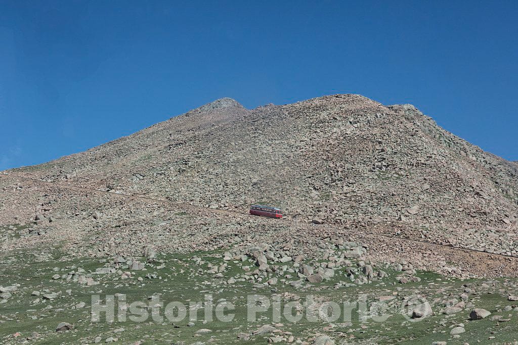 Photo- Distant view, above the treeline, at the Pikes Peak Cog Railway, which ascends Colorado's famous 14,115-foot Pikes Peak from its base station far below in Manitou Springs